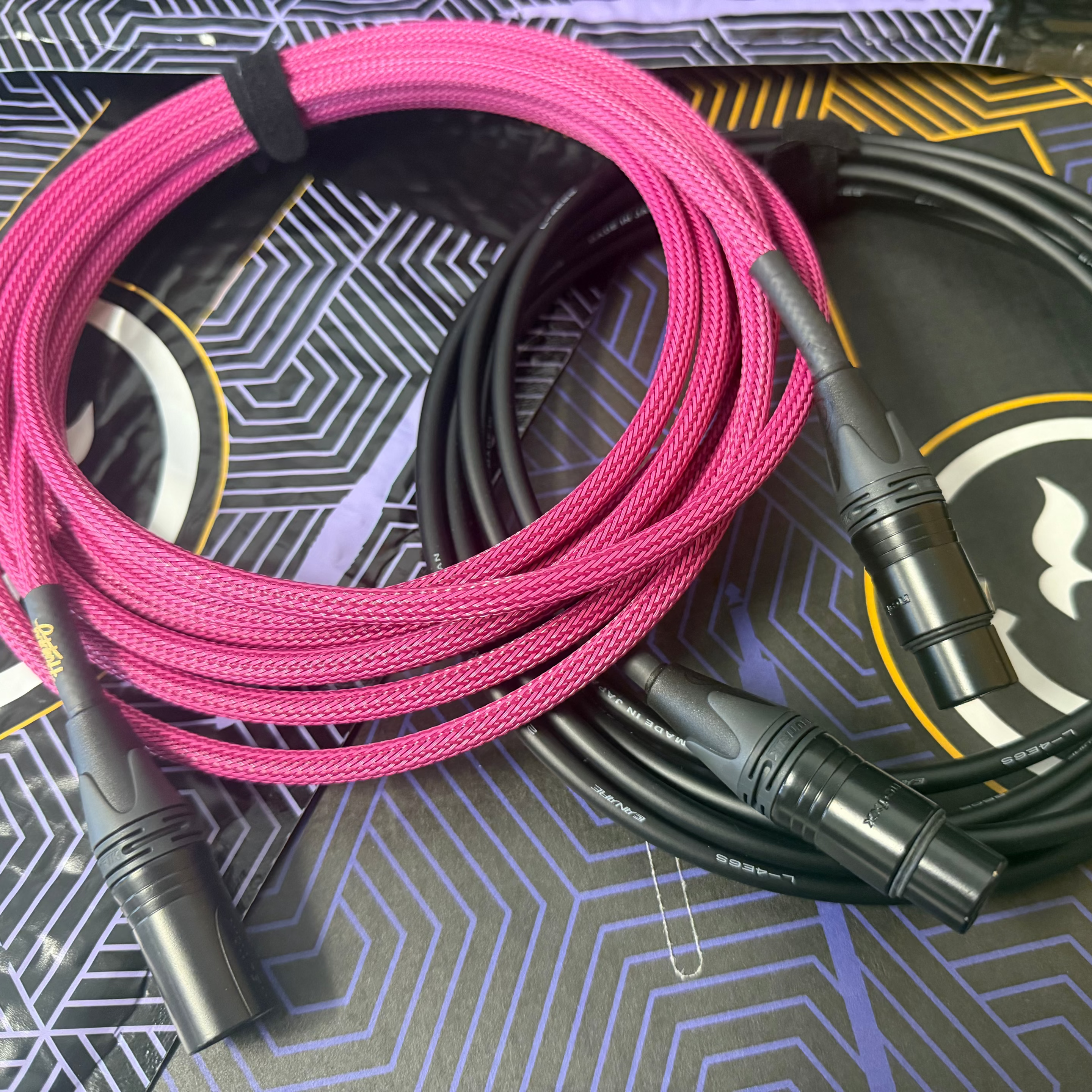 Pink and black audio xlr cables on a patterned surface